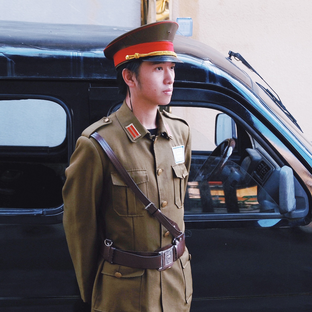 boy in military costume by a vintage black car