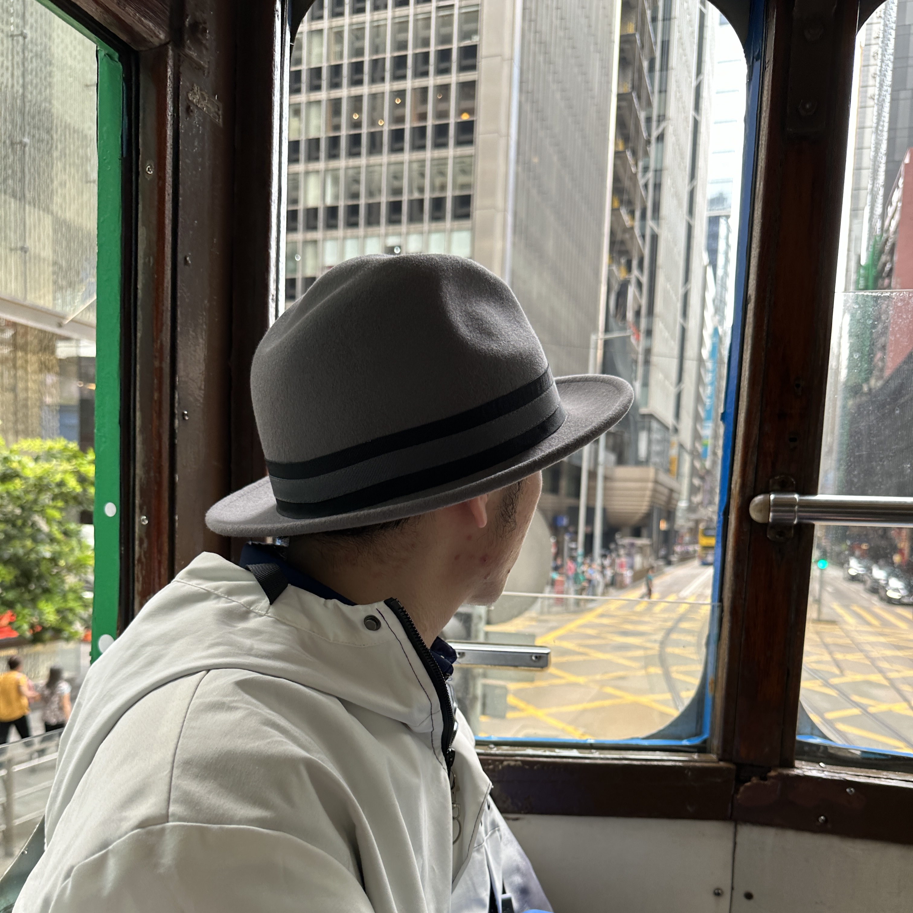 side view of person wearing grey hat and looking outside a tram